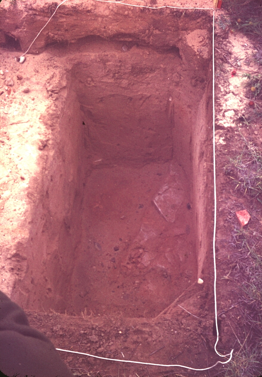 A deep excavation reveals a layer of slabs of limestone at the bottom.