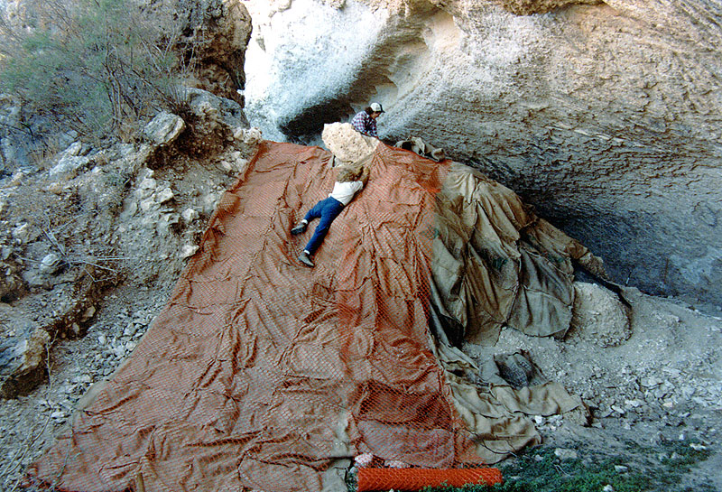 Linda Sattler stretches to tack down the protective covering over the talus cone, while Jeanine McDonald spreads out more burlap bags. 