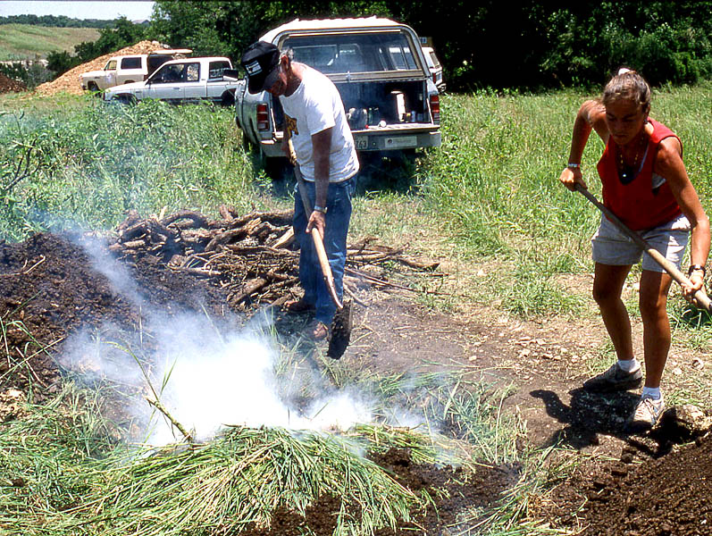 photo of two people shoveling dirt on top of a mound of  grass