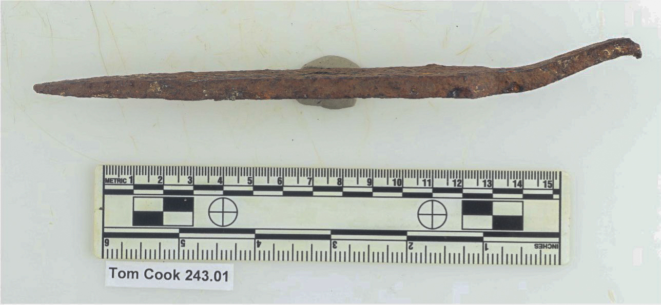 color photo of a side view of a rusty clinching bar with a scale bar below it
