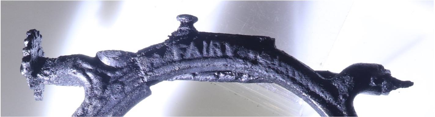 color photo of the top of a cast iron sewing machine which reads FAIRY in raised letters.