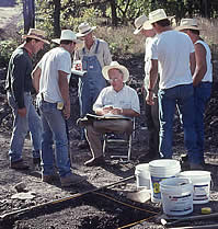 Major excavations began again in 1998 at the Gault site. Here archeologists in standard-issue white cowboy hats gather around Dr. Tom Hester who is examining a Clovis artifact.
