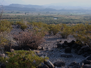  photo of a circular pattern of rocks in the foreground and a river valley in the background