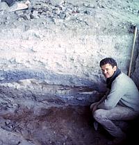 Archeologist Mark Parsons exposes a fiber layer in an undisturbed area of Fate Bell Shelter. The distinctly colored and textured layers visible in the excavation wall represent different episodes in the shelter's long history of intermittent human occupation. Generally speaking, the dark layers are associated with intense occupation, while the light colored layers are mostly cave dust and roof spalls from periods when the shelter (or just this part of it) wasn't used by humans. Photo from ANRA-NPS Archives at TARL.