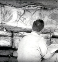 Photo of Kirkland looking at pictographs as he reproduces them in watercolor