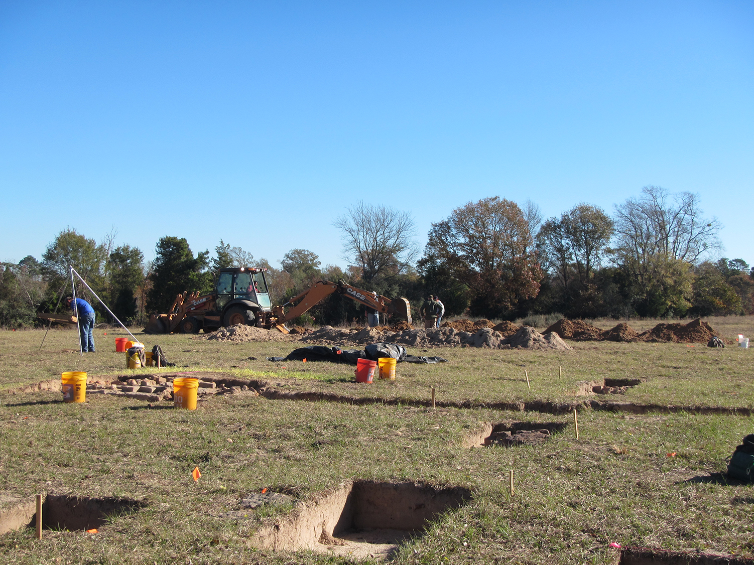 Photo of archeologists digging shovel tests in middle of open field.