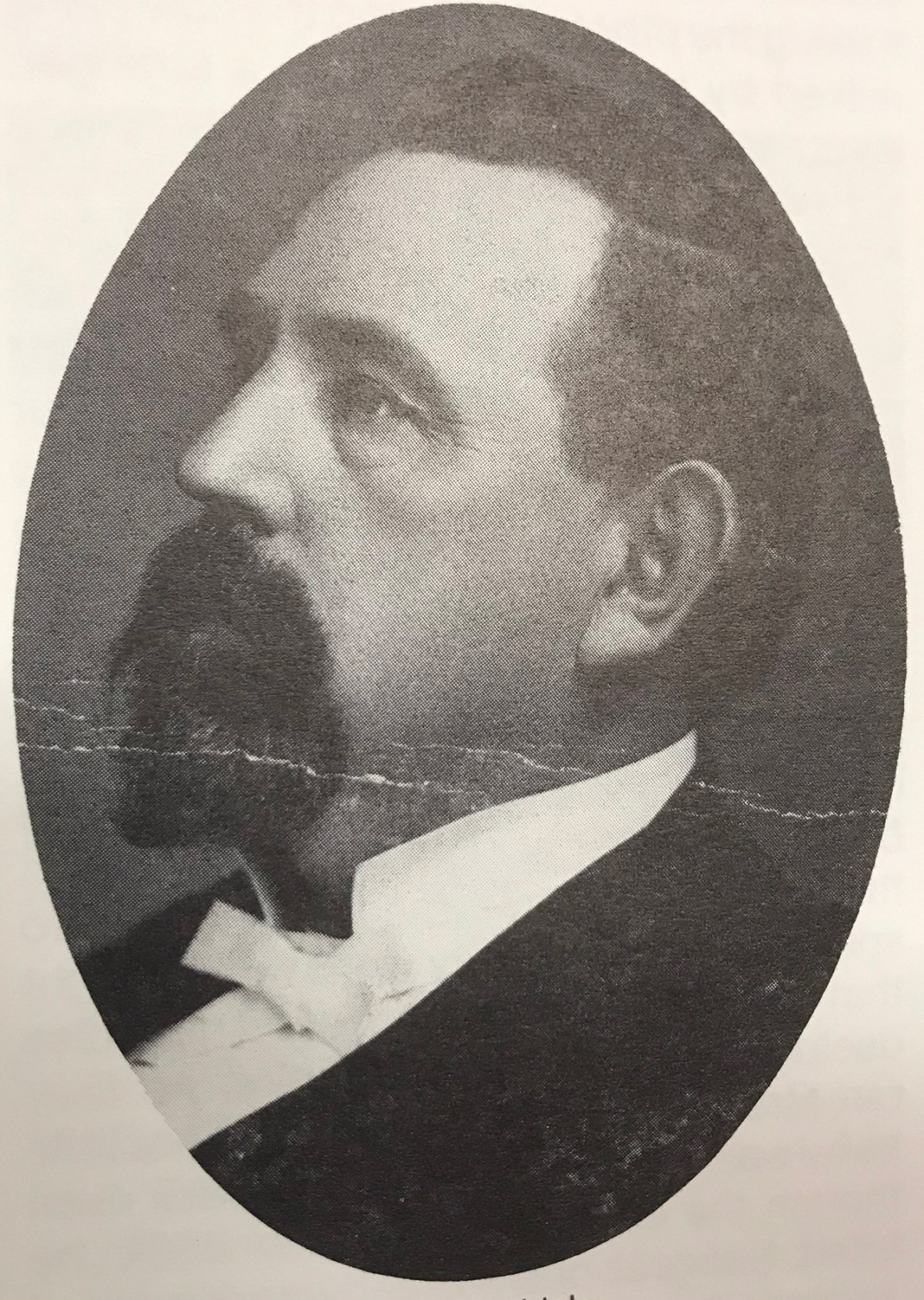 Black and white copy of an oval photograph of a portrait of a Euro-American man in profile with brown hair, looking toward the upper left.