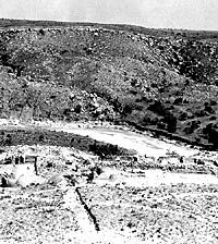 B&W photo looking down on partially excavated ruins from a distance.