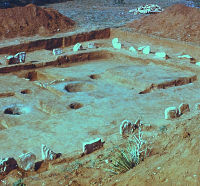 Photo of rectangular pattern of white stones marking the outer walls of a house. 