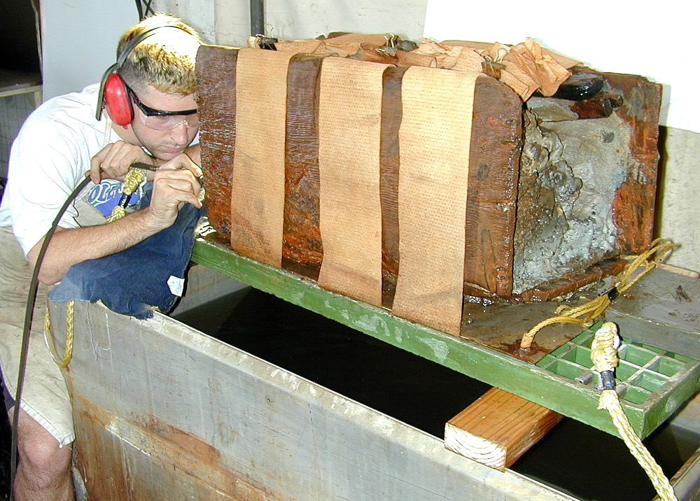 photo of analyst Michael West using an air scribe to separate the boards of the chest from the internal matrix
