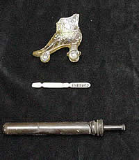 Artifacts from a privy located behind the site of a tenement building on the City Hall block. From top to bottom, a decorative glass roller skate, a bone make-up brush, and a  syringe. Photo courtesy Hicks & Co.