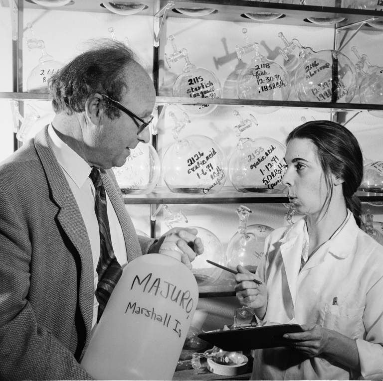 black and white photo of man and woman in lab holding equipment