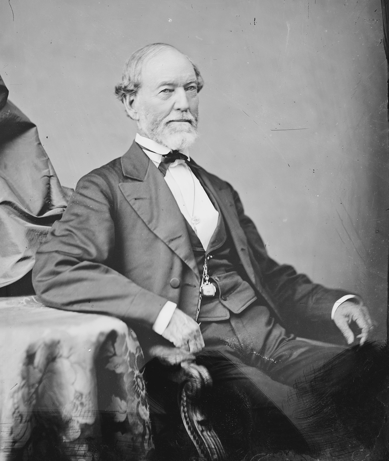 black and white photo of seated well-to-do man in formal clothing