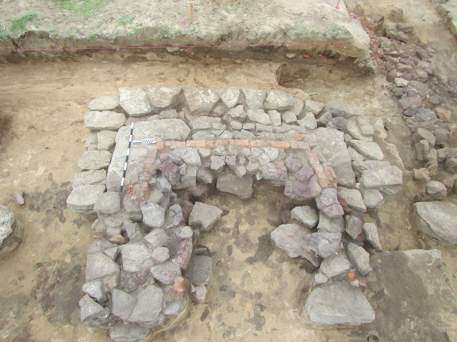 Photo of excavation exposure of U-shaped arrangement of bricks.