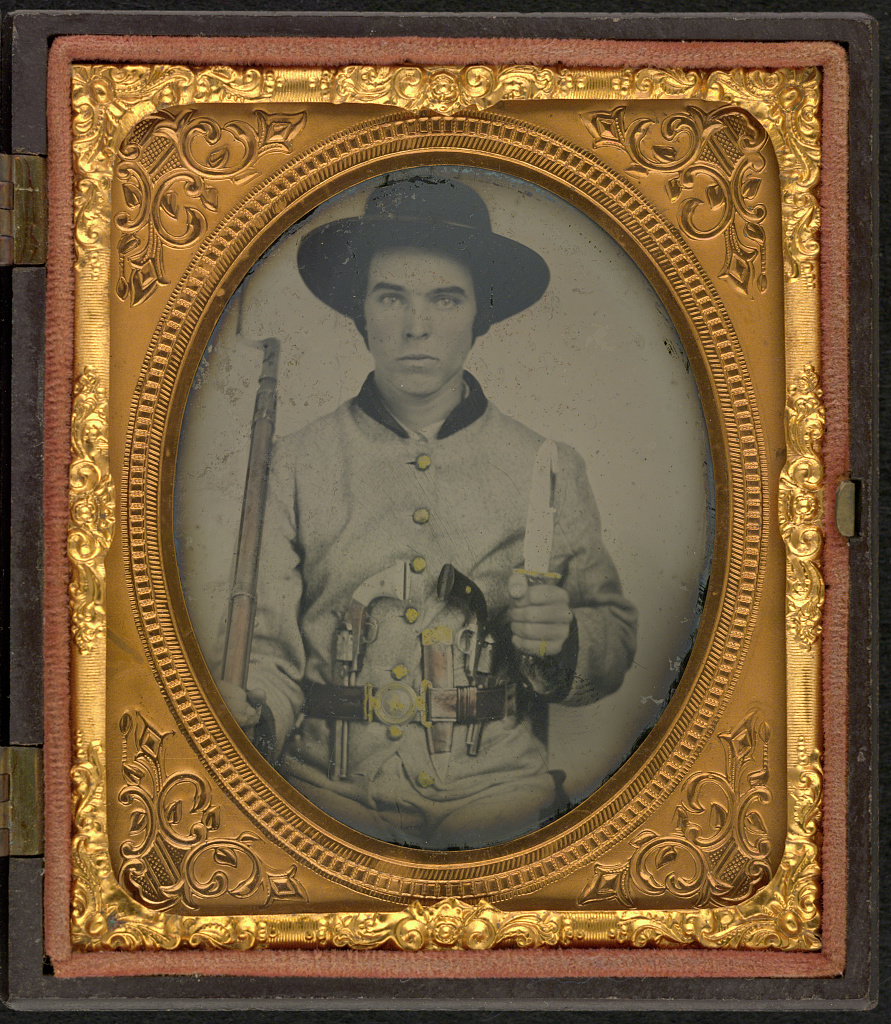 oval black and white photo of young man within gold-guilded display frame.